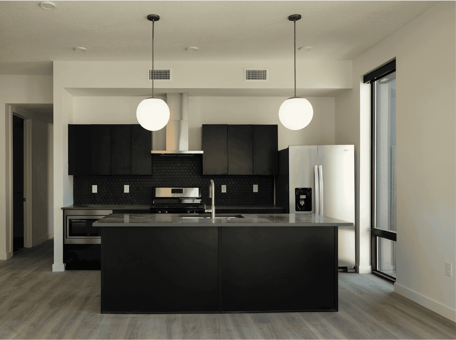 Stylish kitchen showcasing black cabinets alongside a stainless steel refrigerator