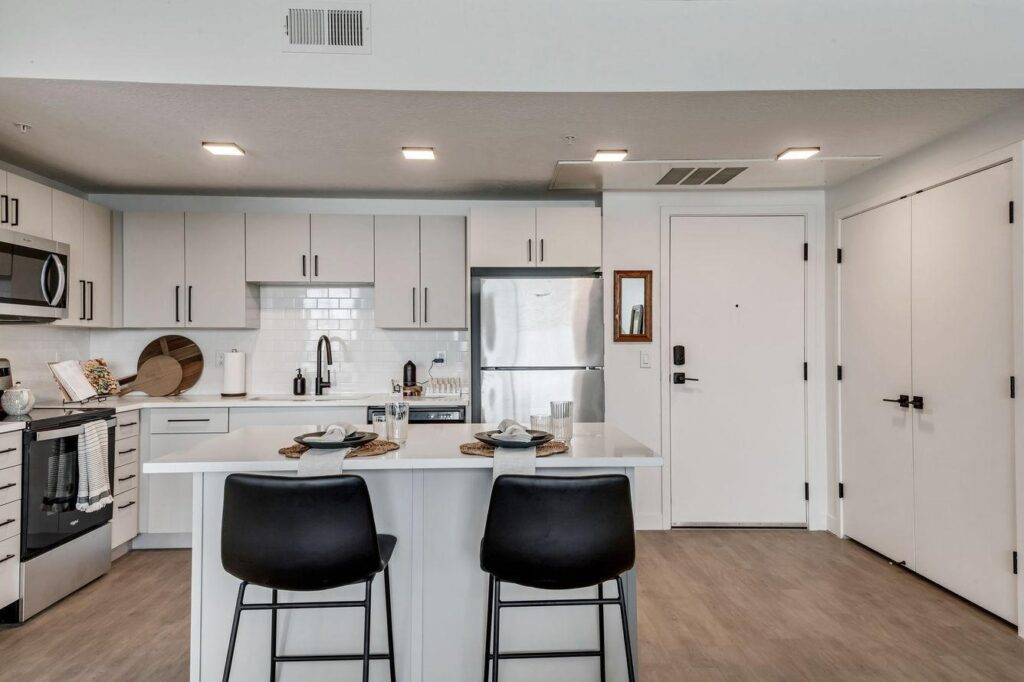 A modern kitchen featuring white cabinets and sleek black chairs arranged around a dining table