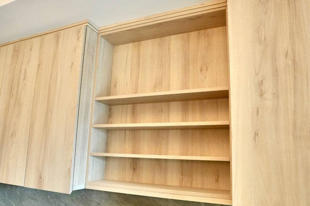A kitchen featuring wooden shelves and cabinets, designed by scs Multifamily, showcasing a warm and inviting atmosphere.

