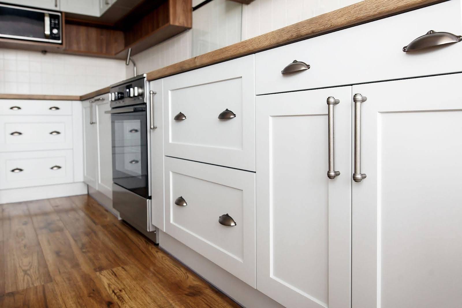 A bright white kitchen featuring wooden floors and white cabinets conveying a clean and modern design