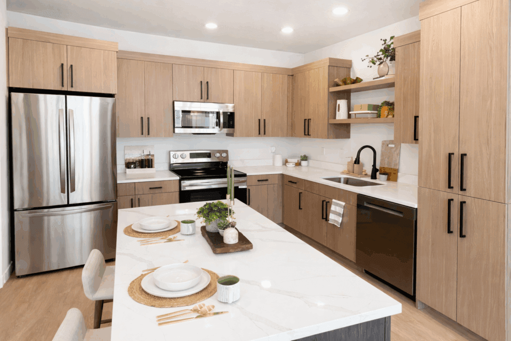 A modern kitchen featuring stainless steel appliances and elegant wood cabinets, designed by SCS Multifamily.