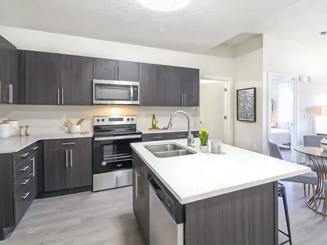 A modern kitchen featuring stainless steel appliances and a cozy dining area, designed by SCS Multifamily.