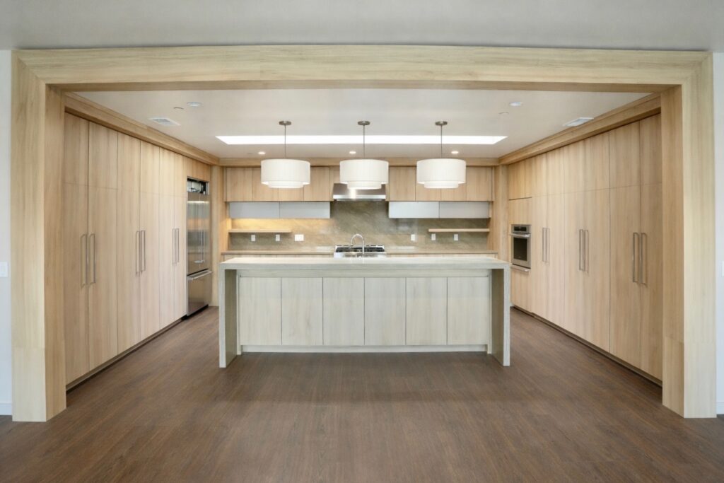 A modern kitchen featuring wooden cabinets and a central island, designed by SCS Multifamily.