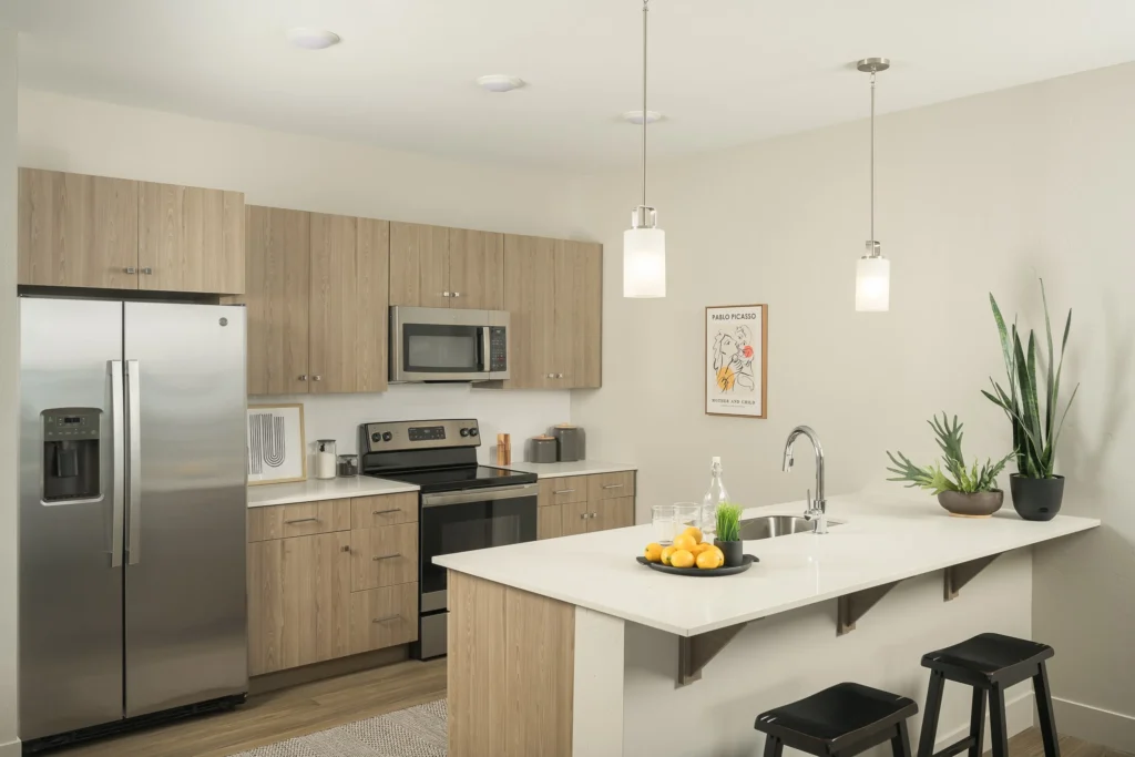 A modern kitchen featuring stainless steel appliances and wooden cabinets, designed by SCS Multifamily.